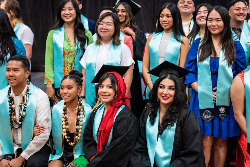 API student graduates pose with their teal stoles.